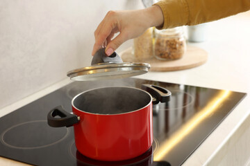 Woman cooking dinner on cooktop in kitchen, closeup