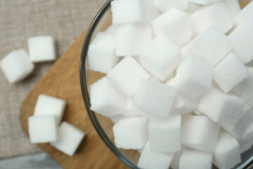 White sugar cubes in glass bowl on grey table, top view