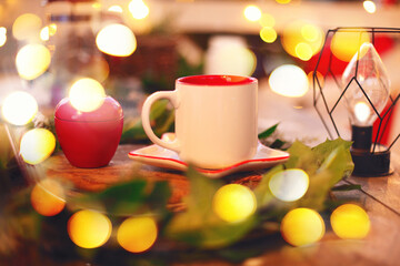 Obraz na płótnie Canvas White cup of hot winter drink on blurred Christmas background with yellow xmas lights