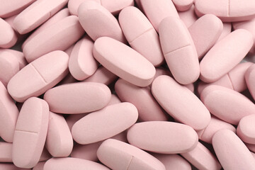 Pink vitamin capsules as background, top view