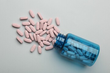Vitamin pills and bottle on grey background, top view