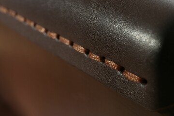 Dark leather with brown seam as background, closeup