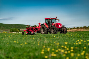 Red Tractor with Seeder in Lush Green Field