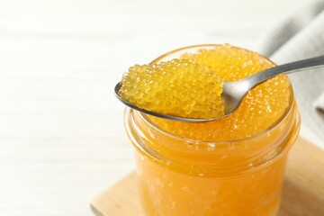 Taking fresh pike caviar from glass jar on white table, closeup. Space for text