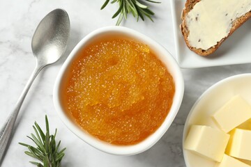 Fresh pike caviar in bowl, bread, rosemary and butter on white marble table, flat lay