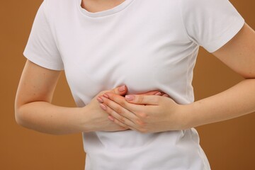 Woman having heart attack on brown background, closeup