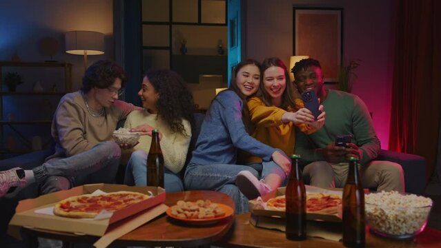 Couple eating popcorn while friends taking selfie at party