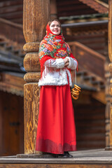 A beautiful Russian girl in red traditional Russian clothes holds bagels in her hands in the spring...