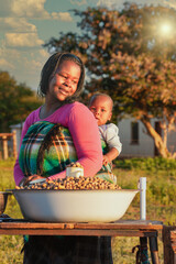 young village street vendor african woman with braids holding her baby