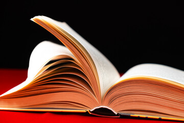 Pages of a thick book are turned on a red and black background.