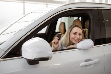 Auto business, car sale, consumerism and people concept. Happy Caucasian woman taking car key from...