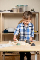 Little boy making cookies using cookie cutters and dough in the kitchen.