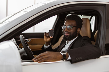 Auto business, car sale, consumerism and people concept. Happy African man taking car key from...