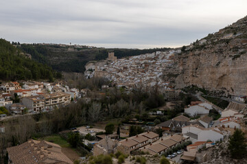 Fototapeta na wymiar Panoramic view of the town of Alcalá del jucar from Las Eras viewpoint. Its popular cave houses, carved into the mountain, the castle and Church of San Andrés in the gorge of the jucar river, Albacete