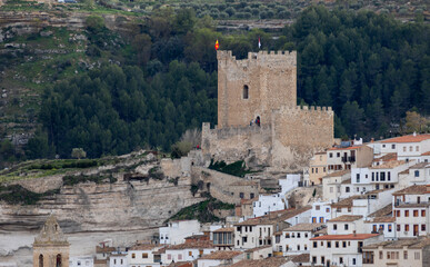 Obraz premium Panoramic view of the town of Alcalá del jucar from Las Eras viewpoint. Its popular cave houses, carved into the mountain, the castle and Church of San Andrés in the gorge of the jucar river, Albacete