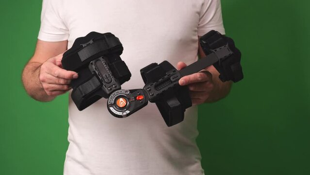 Rehabilitating an injured elbow, a man demonstrates how to adjust his brace for optimal healing, flexing his arm to show the device.