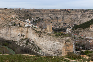 Fototapeta na wymiar Panoramic view of the town of Alcalá del júcar from Casas del Cerro. Its popular cave houses, carved into the mountain, the castle and Church of San Andrés in the gorge of the júcar rive, Albacete.