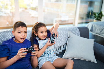 Children, siblings and video game with controller, sofa and online for esports in home. Technology,...