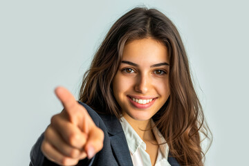 Young smiling woman pointing finger at viewer on light blue background. Winner, job candidate and selection concept