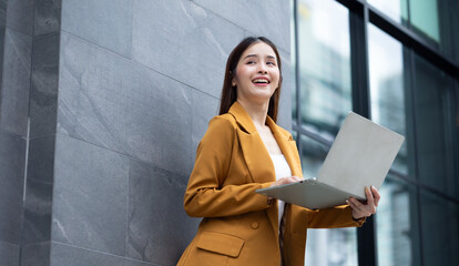 businesswoman - Successful business woman working with laptop computer standing near office building. City businesswoman working