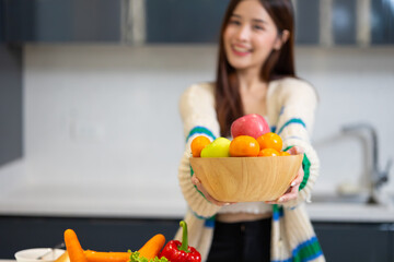 Diet weight and healthy foods concept - Portrait of smiling happy Asian girl holding bowl of fruit orange apple.  healthy food for health