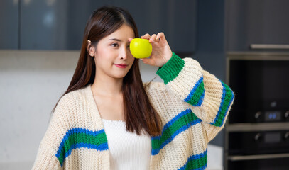 Diet weight and healthy foods concept - Portrait of smiling happy Asian girl holding showing green apple fruit against her eyes.  healthy food for health