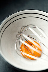 Egg yolk with a whisk in a ceramic bowl