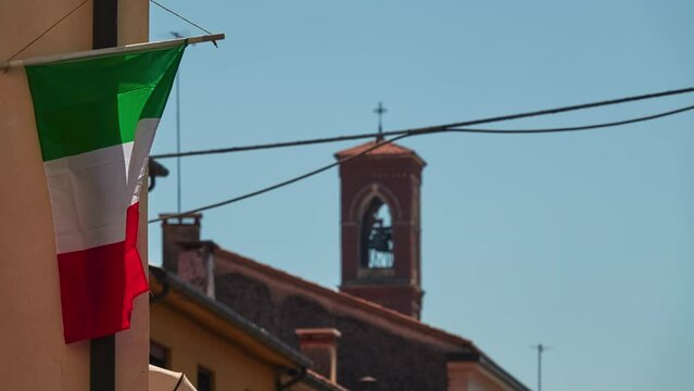 Tricolor flag of Italy flutters in the wind on an old city building.