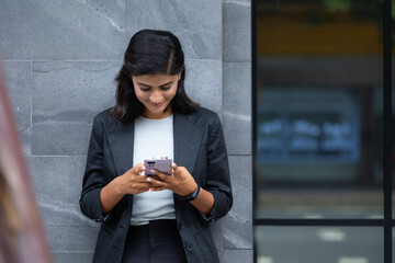Mobile phone technology lifestyle - Portrait Smiling Young Businesswoman in black suit using...