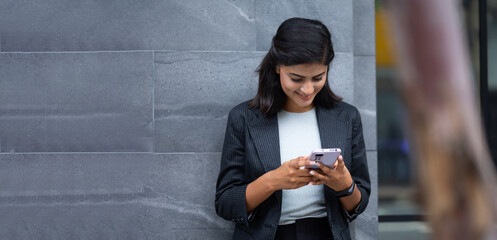 Mobile phone technology lifestyle - Portrait Smiling Young Businesswoman in black suit using...