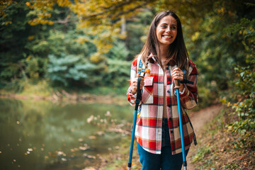 Photo of a young smiling woman carrying a backpack and hiking in the nature. Young woman breathing...