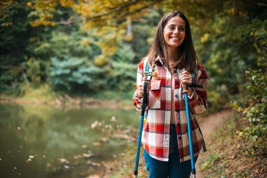 Photo of a young smiling woman carrying a backpack and hiking in the nature. Young woman breathing pure air in a forest. Happy hiker caucasian woman smile and enjoy the nature walking
