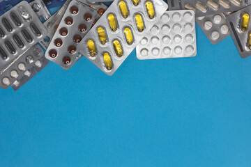 Many colorful blisters pills, capsules blue background, copy space, top view, mockup, flat lay....