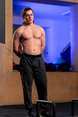 Obraz premium in a sports club guy trainer in black sweatpants stands near the floor horizontal bar
