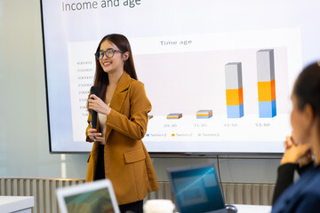 Presentation - Asian business woman people giving presentation and Report pointing at projector or...
