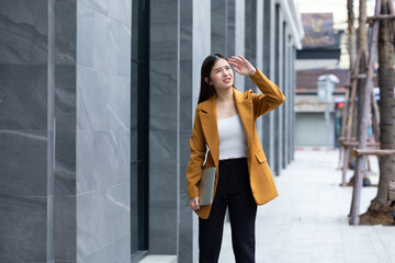 Skin care and sun UV protection - Portrait Successful business woman in yellow suit walking outdoors and use hand protection UV sunlight on street office building. walking city urban street