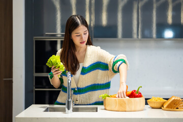 Wash vegetables - Asian young woman Fresh Vegetables washing in the kitchen. Clean food by water