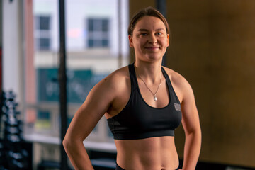 in a sports club trainer in a black top and leggings stands and poses smiling