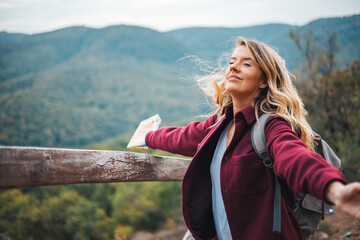 Woman contemplating a beautiful landscape. Young woman breathing pure air in a forest. Young woman hiking and going camping in nature. Person with backpack walking in the forest - 786265349