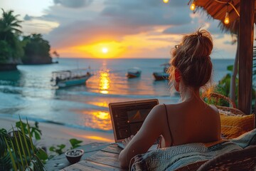 Female freelancer with laptop on the beach during sunset. Place of work of a hermit freelancer. A symphony of colors as the female freelancer creates her own twilight oasis.