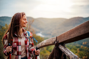 Young woman hiking in Autumn, mountain landscape.  Woman hiking with hiking pole on mountain...