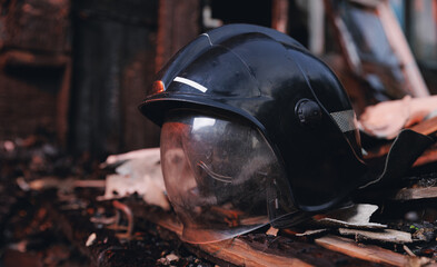 Helmet against background of burn and burnt house. Concept firefighter died while on duty in fire