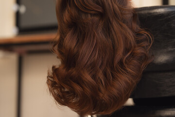 Detailed view of shiny hair highlighting its natural curls and texture background. Woman head showcasing styled auburn hairstyle with soft waves