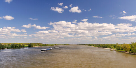The Waal river west of Nijmegen with cargo ship passing by in The Netherlands