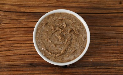 Delicious nut butter in bowl on wooden table, top view