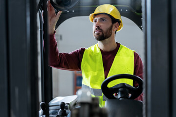 Confident, bearded, attractive man, worker, driver wearing hard hat, work wear driving forklift