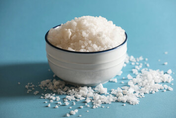 Organic salt in bowl on light blue background, closeup
