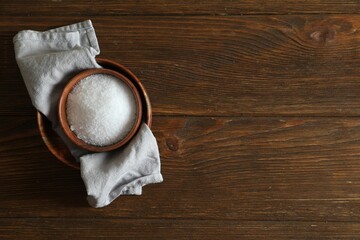 Organic salt in bowl on wooden table, top view. Space for text