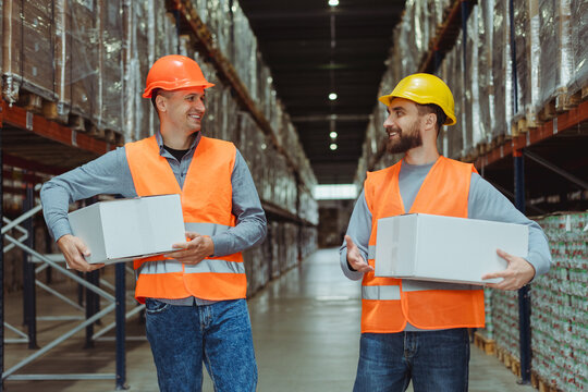 Smiling men, successful workers wearing hard hats, work uniforms holding boxes, mockup talking