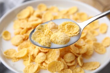 Breakfast cereal. Eating corn flakes and milk with spoon from bowl on table, closeup
